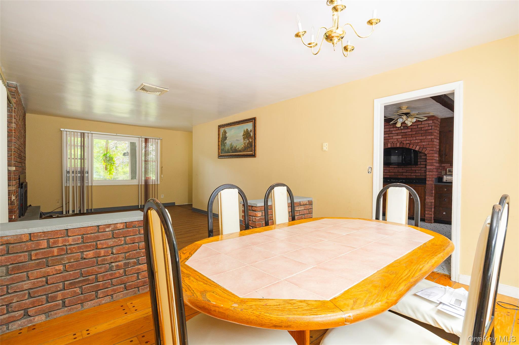 993 Highway 32 Wallkill, NY 12589 - Photo 24 of 35 Dining space with brick wall, wood finished floors, and a chandelier