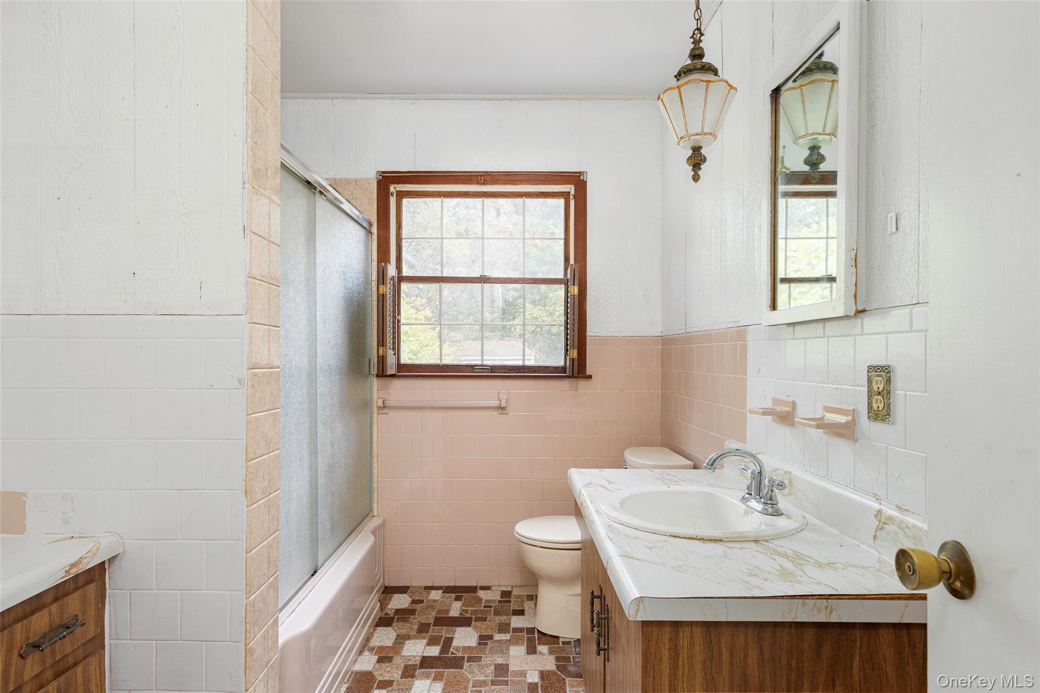 993 Highway 32 Wallkill, NY 12589 - Photo 34 of 35 Full bathroom featuring vanity, enclosed tub / shower combo, tile walls, plenty of natural light, and a wainscoted wall