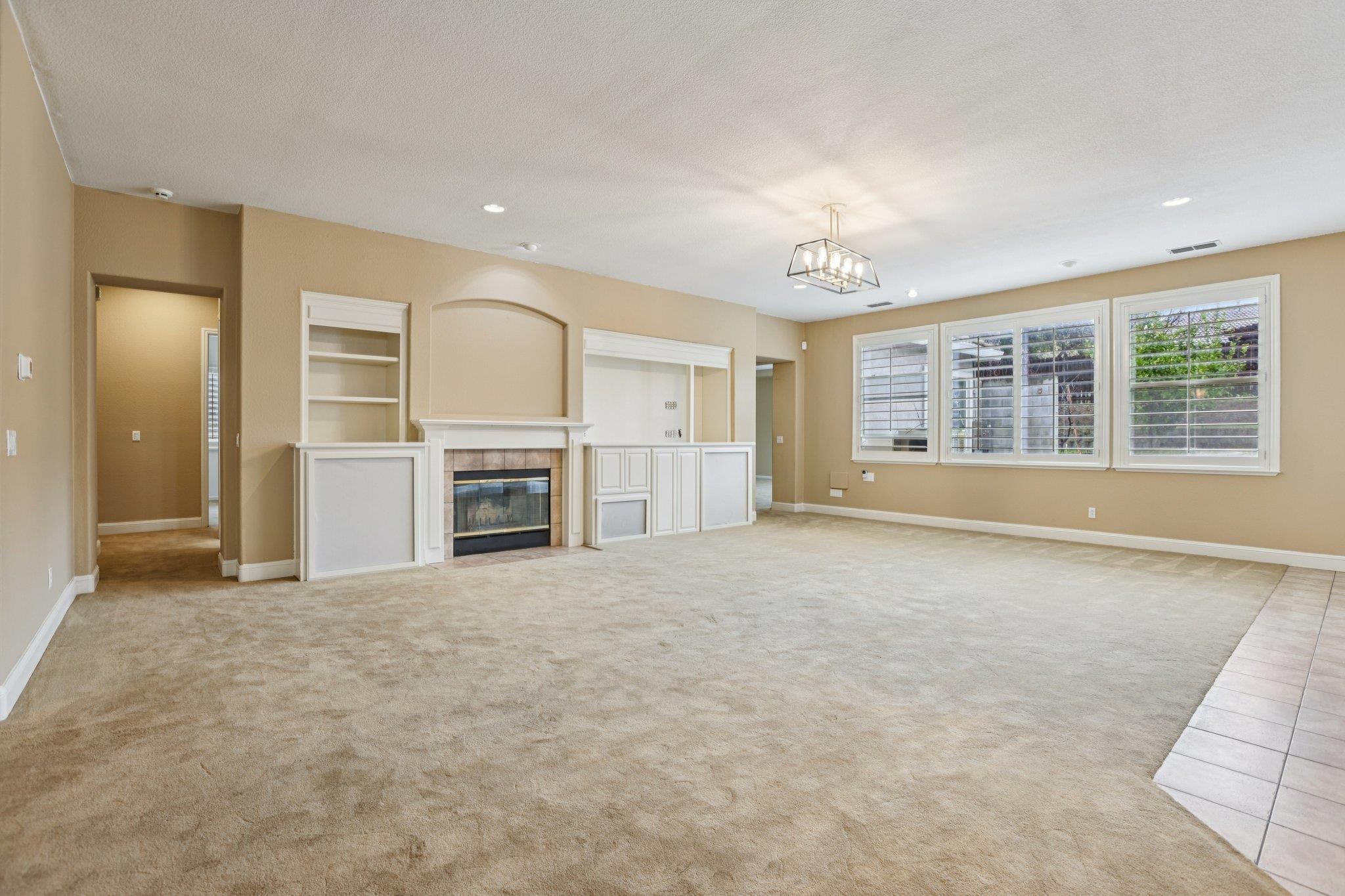 5227 Ramsdell Court Antioch, CA 94531 - Photo 7 of 58 Unfurnished living room with light colored carpet, a tile fireplace, recessed lighting, built in shelves, and a textured ceiling
