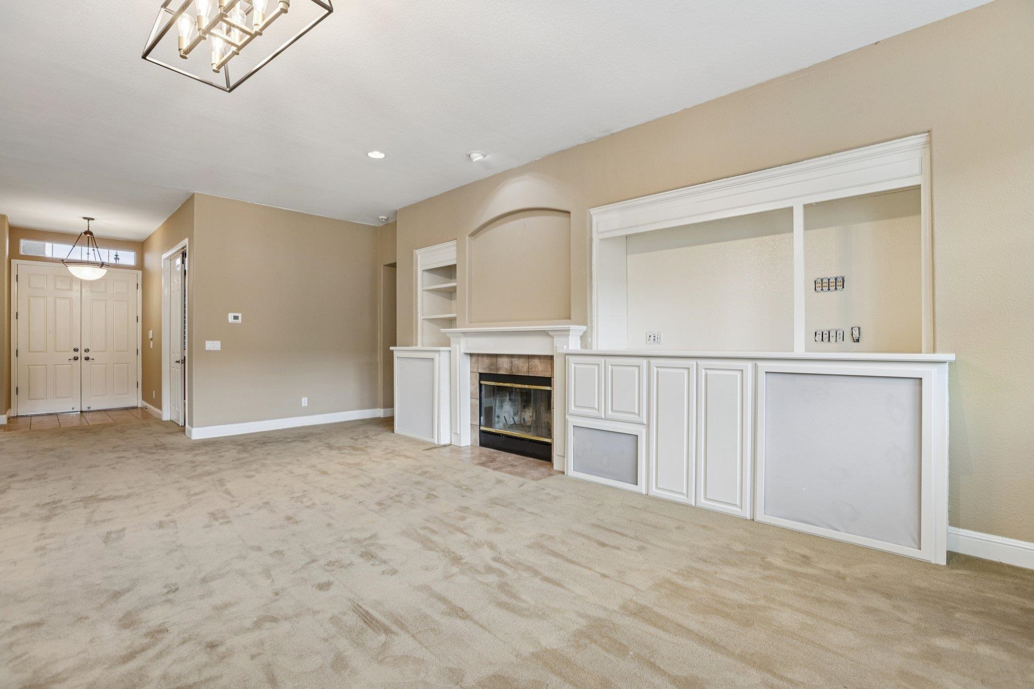 5227 Ramsdell Court Antioch, CA 94531 - Photo 8 of 58 Unfurnished living room with light colored carpet, built in shelves, and a tile fireplace