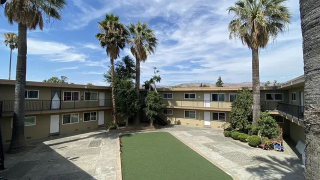 a front view of a house with a garden and palm trees
