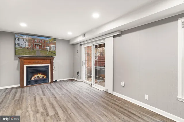 an empty room with wooden floor a fireplace and windows