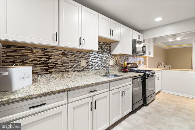 a kitchen with granite countertop white cabinets and white appliances