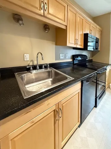 a kitchen with granite countertop a sink a stove and cabinets