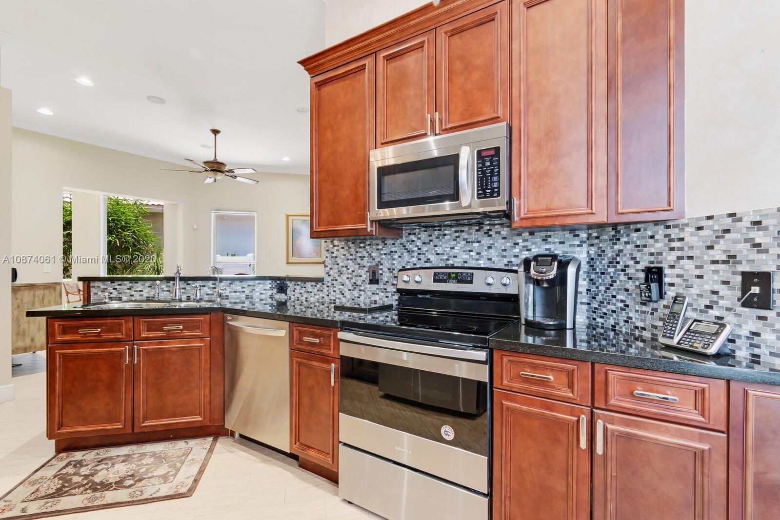 23434 Rakelle Circle Boca Raton, FL 33433 - Photo 3 of 40 a kitchen with stainless steel appliances granite countertop a stove a sink and a microwave