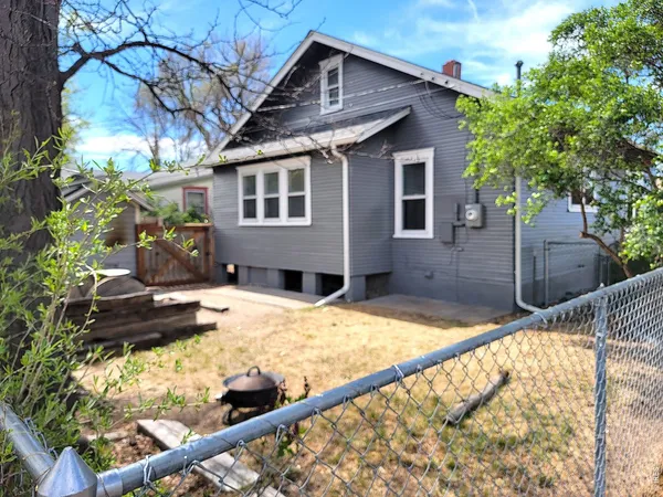 a backyard of a house with wooden fence and large trees