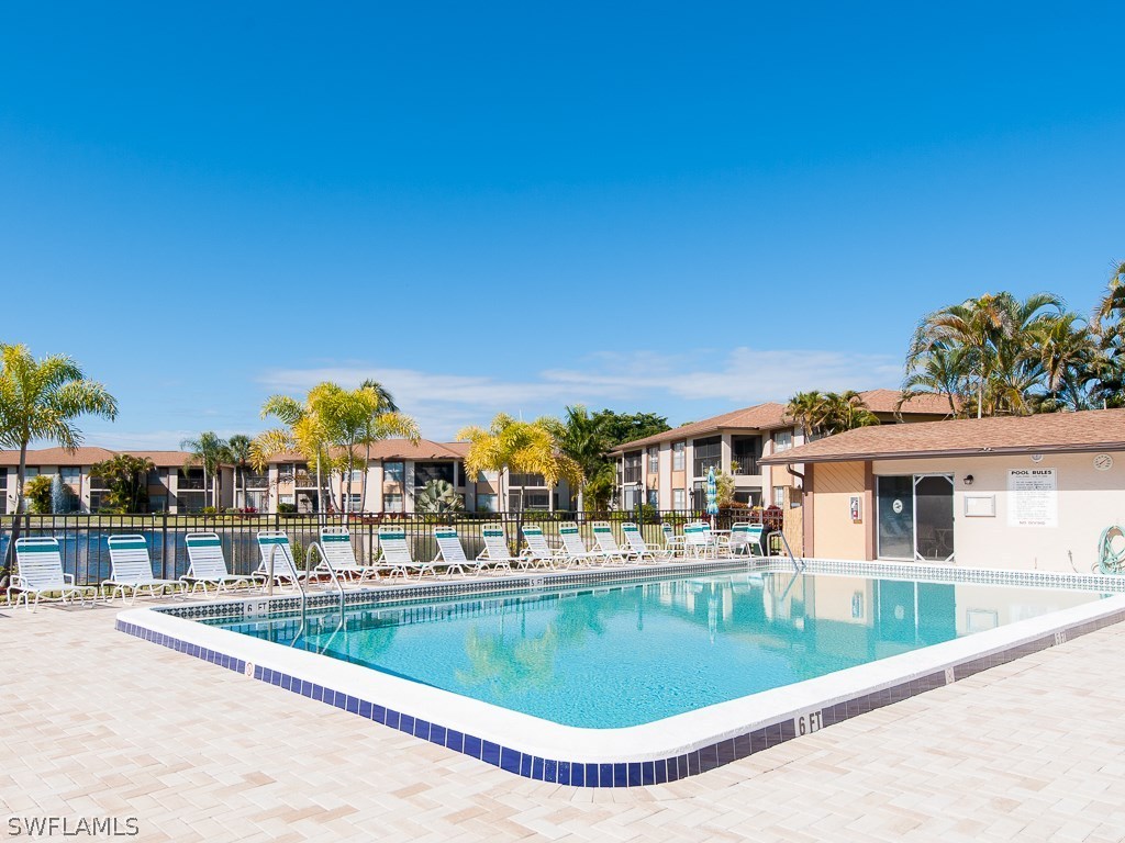 16881 Davis Road, Unit 414 Fort Myers, FL 33908 - Photo 20 of 24 a view of a swimming pool with a lawn chairs under an umbrella
