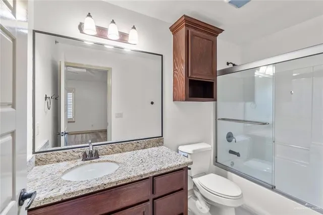 a bathroom with a granite countertop sink toilet mirror and shower