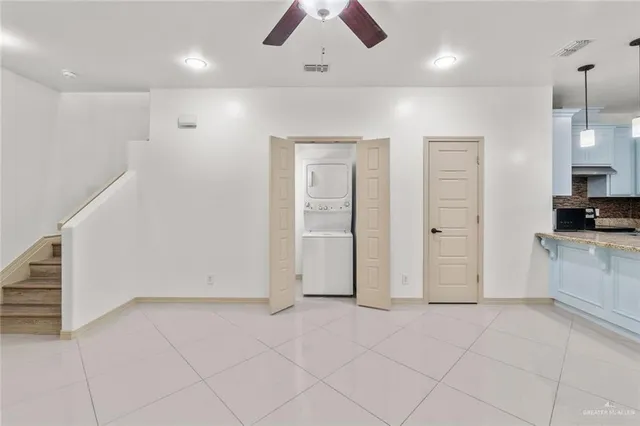 an empty room with kitchen and chandelier fan