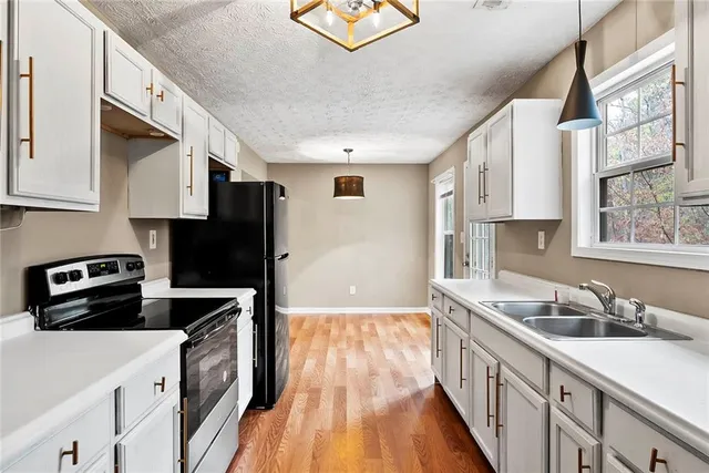 a kitchen with granite countertop a sink a stove and refrigerator