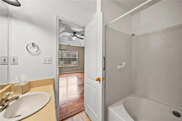 a bathroom with a granite countertop sink a mirror and a bathtub