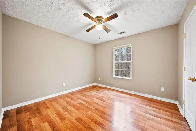 an empty room with window and ceiling fan