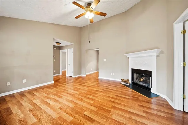 a view of an empty room with a fireplace and a chandelier fan