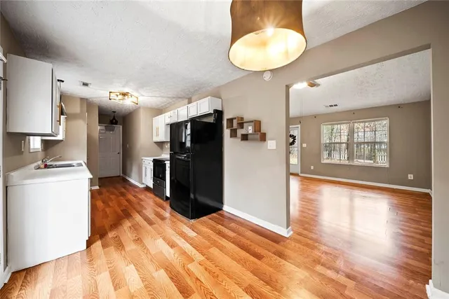 a view of a kitchen with refrigerator and wooden floor