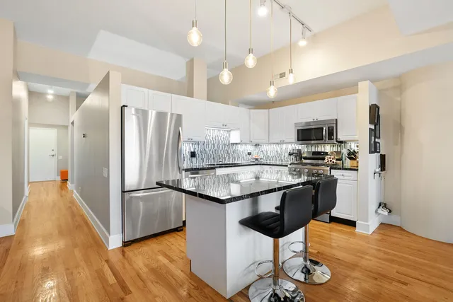 a kitchen with stainless steel appliances kitchen island granite countertop a refrigerator and a stove top oven