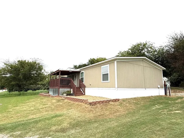 a front view of house with yard and trees in the background