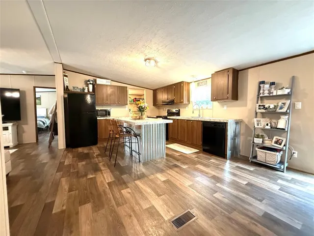 a kitchen with stainless steel appliances kitchen island granite countertop a refrigerator and cabinets
