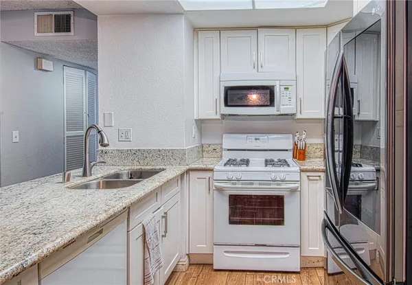 a kitchen with granite countertop a stove sink and refrigerator