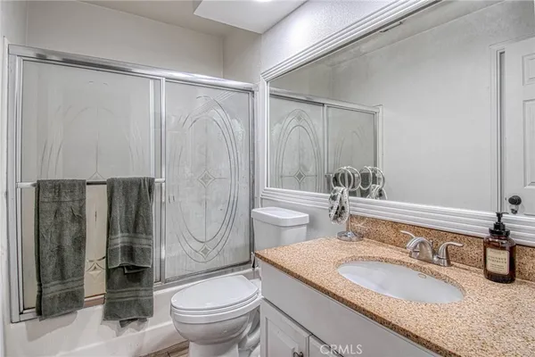 a bathroom with a granite countertop sink toilet and shower