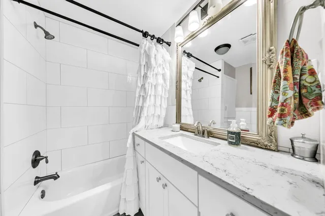 a bathroom with a granite countertop sink mirror and a bathtub