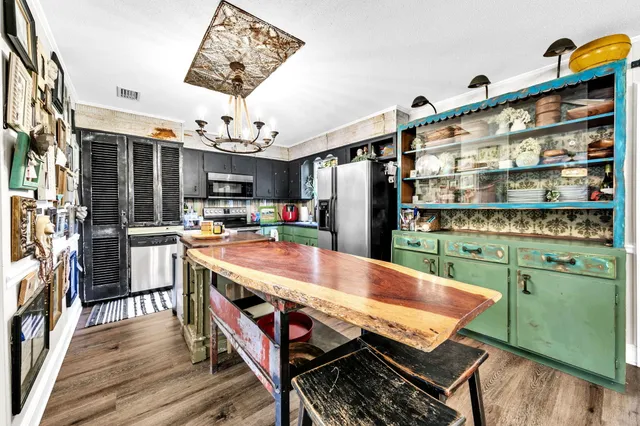 a room with stainless steel appliances kitchen island granite countertop furniture and a wooden floor
