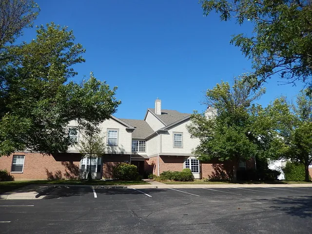 a view of a white house next to a road and yard