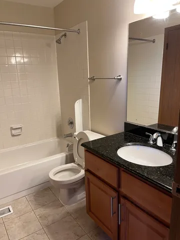 a bathroom with a granite countertop sink toilet a mirror and shower