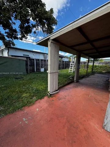 a view of a backyard with plants and large trees