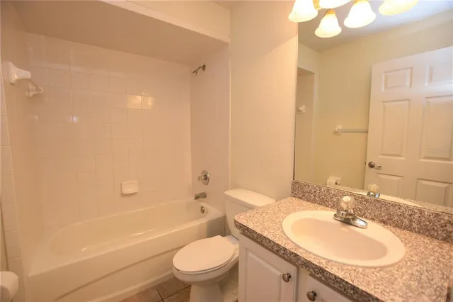 a bathroom with a granite countertop sink a toilet and shower