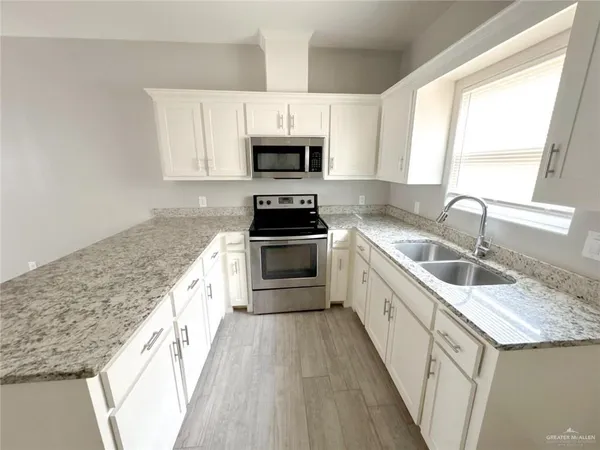 a kitchen with stainless steel appliances granite countertop a refrigerator a stove and a sink