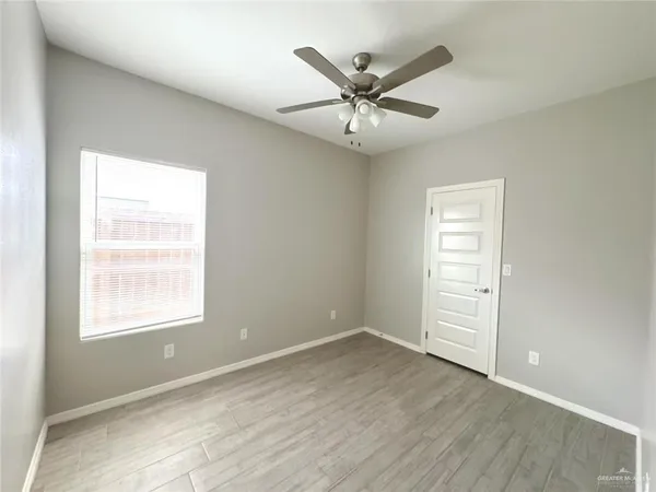 an empty room with wooden floor closet and windows