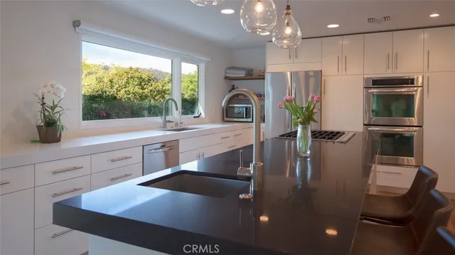 a kitchen with stainless steel appliances a dining table chairs refrigerator and sink