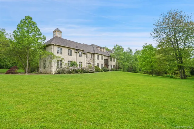 a view of a big house with a big yard and large trees