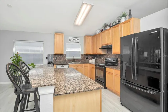 a kitchen with granite countertop stainless steel appliances a counter top space and a window