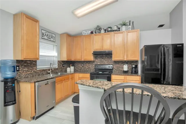 a kitchen with stainless steel appliances granite countertop a sink a stove a refrigerator and island