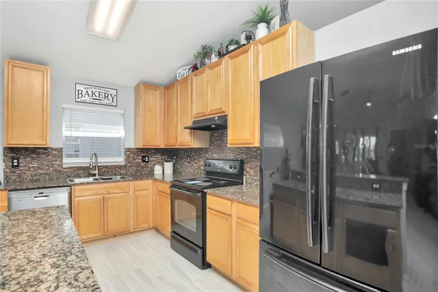 a kitchen with stainless steel appliances granite countertop a sink a stove and a refrigerator