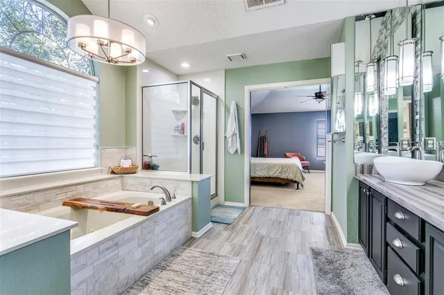 a en suite bathroom with a tub double vanity and a window