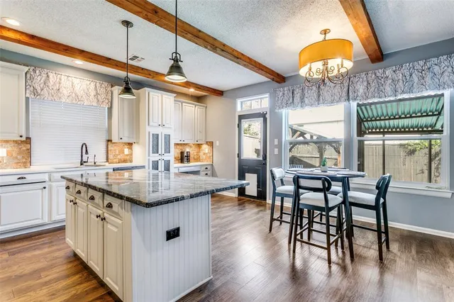 a kitchen with stainless steel appliances granite countertop a table chairs and wooden floors
