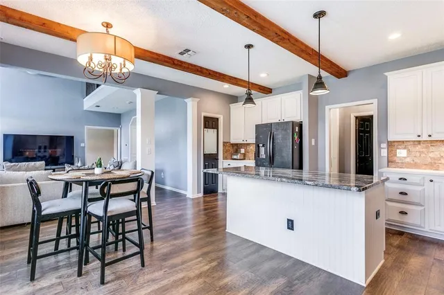 a kitchen with stainless steel appliances kitchen island granite countertop a table chairs and a refrigerator