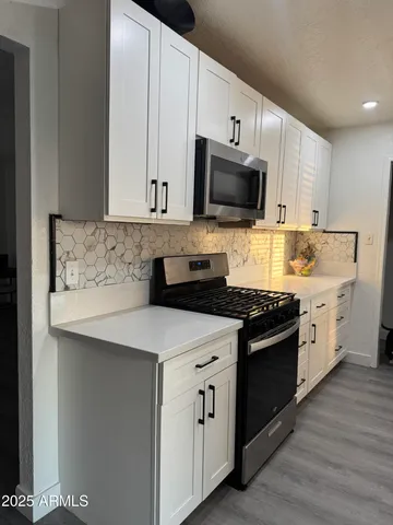 a kitchen with stainless steel appliances granite countertop a stove a sink and a microwave