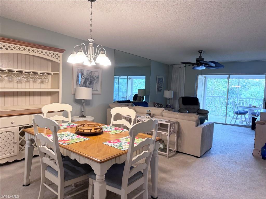 a view of a dining room with furniture a chandelier and large windows