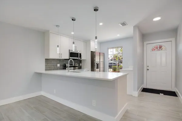 a large kitchen with stainless steel appliances a large counter top a stove and a refrigerator
