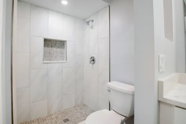 a white toilet sitting next to a shower