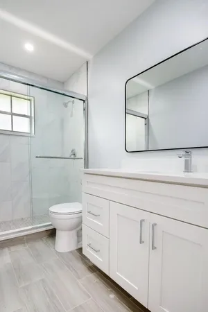 a bathroom with a toilet a sink a shower and mirror