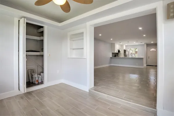 a view of a hallway with wooden floor and a kitchen