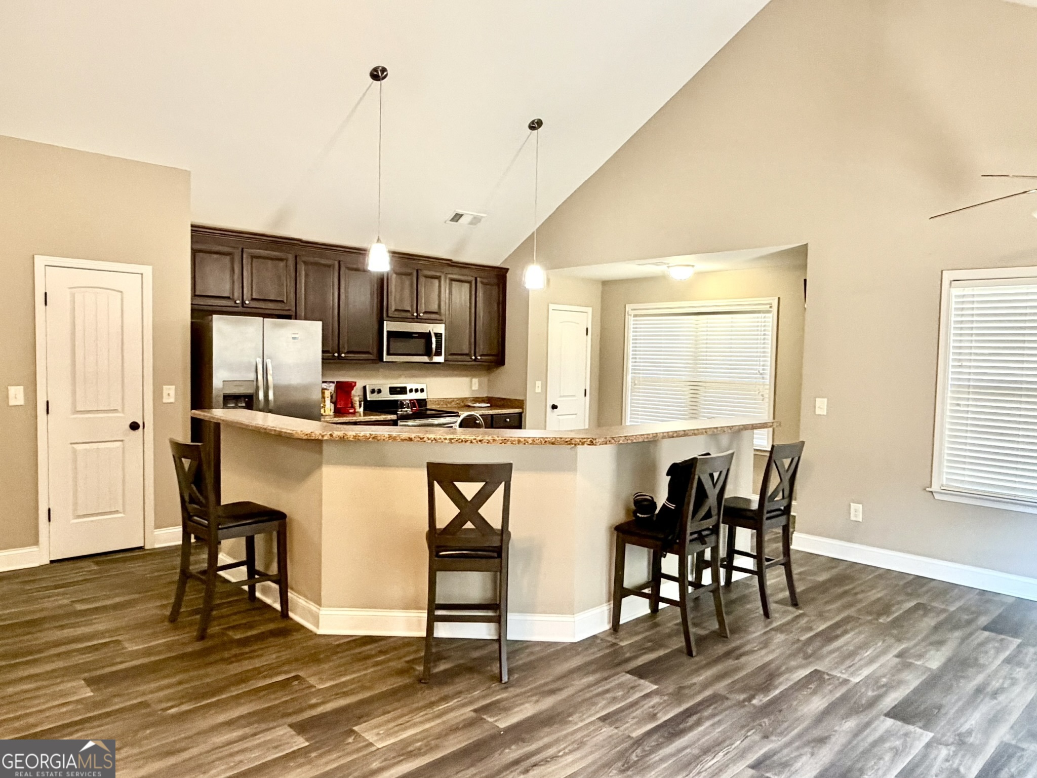 111 Bridle Path Griffin, GA 30224 - Photo 4 of 20 a kitchen with kitchen island granite countertop a stove a sink a dining table and chairs with wooden floor