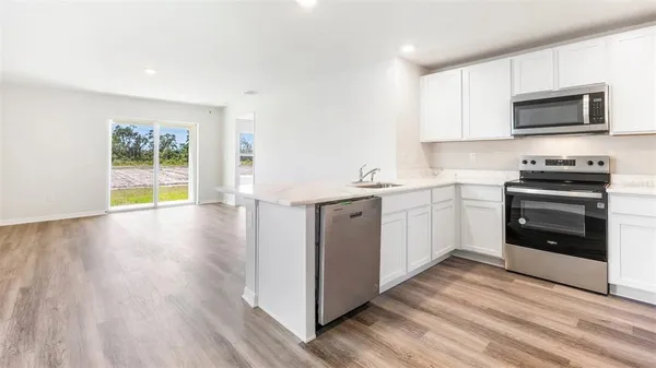 a kitchen with a sink a stove top oven and wooden floor