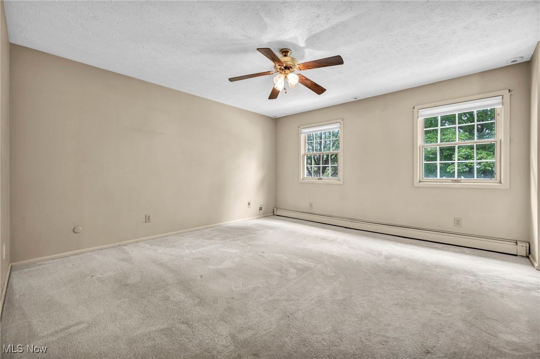 38814 Johnnycake Ridge Road Willoughby, OH 44094 - Photo 29 of 48 Empty room featuring baseboard heating, carpet floors, ceiling fan, baseboards, and a textured ceiling