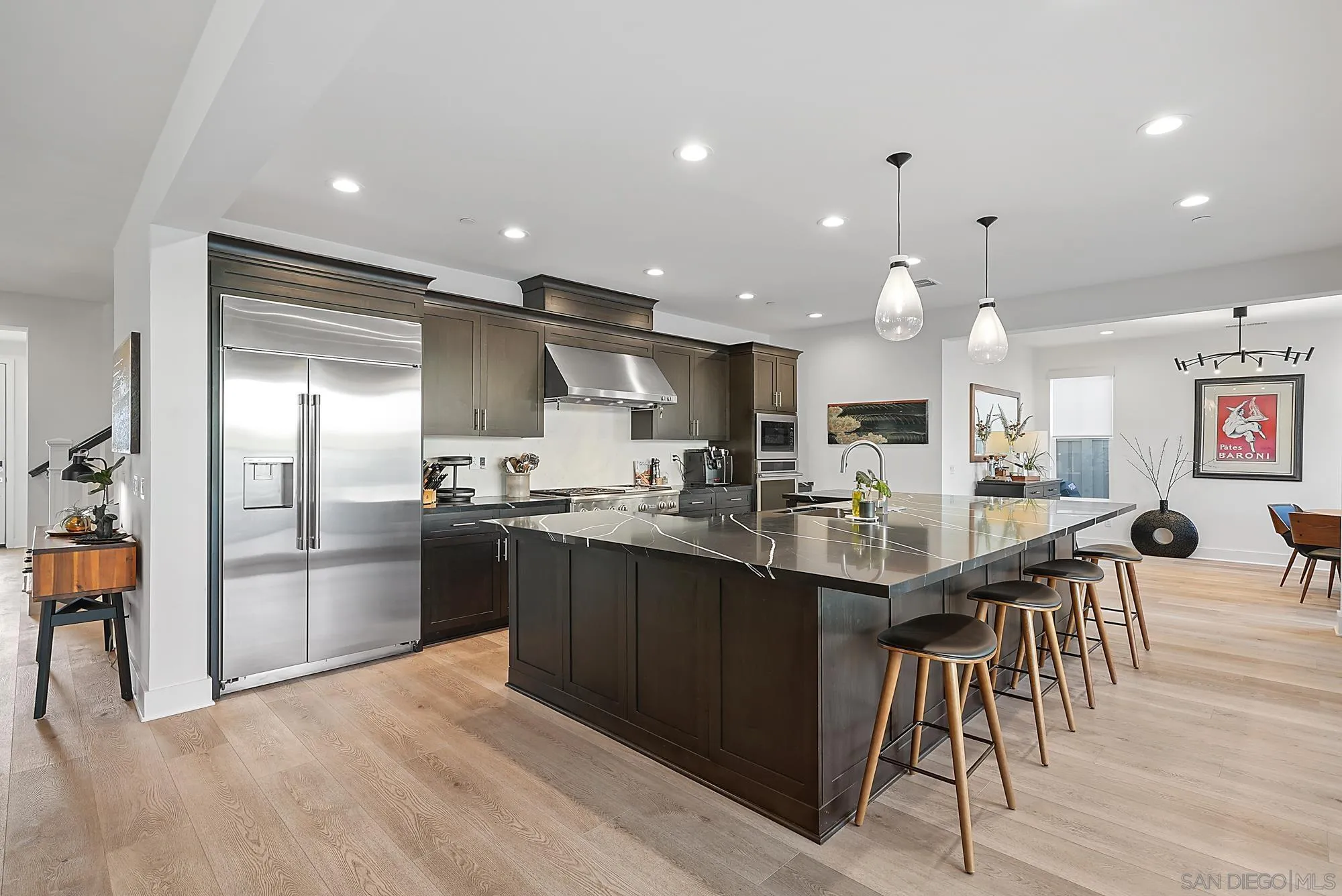 927 Moonstone Court Encinitas, CA 92024 - Photo 15 of 31 a kitchen with stainless steel appliances kitchen island granite countertop a table chairs sink and cabinets