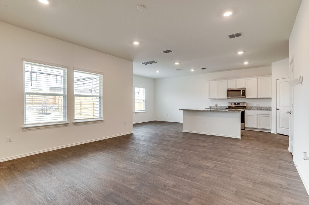 14824 Grey Ghost Way, Unit A Manor, TX 78653 - Photo 4 of 20 a view of kitchen with kitchen island granite countertop a stove top oven a sink and a dishwasher with wooden floor